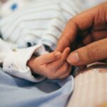 infant holding moms finger