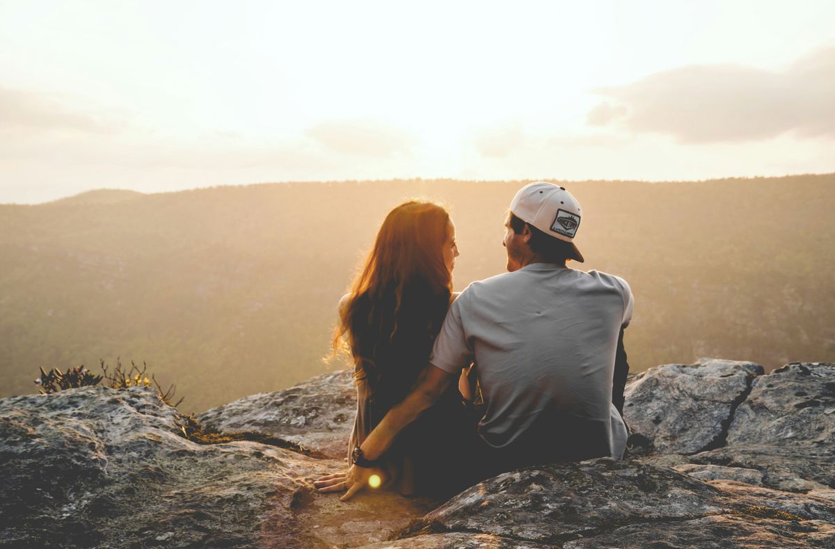 couple sitting together watching sunset on a mountain